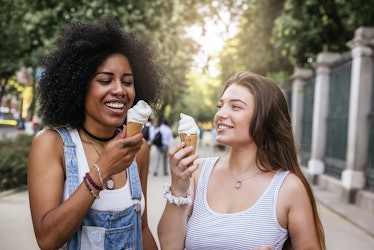 Beautiful women eating one ice cream in the street. Youth concept.