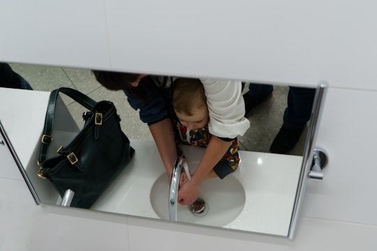 Mom wash hands son in the public restroom