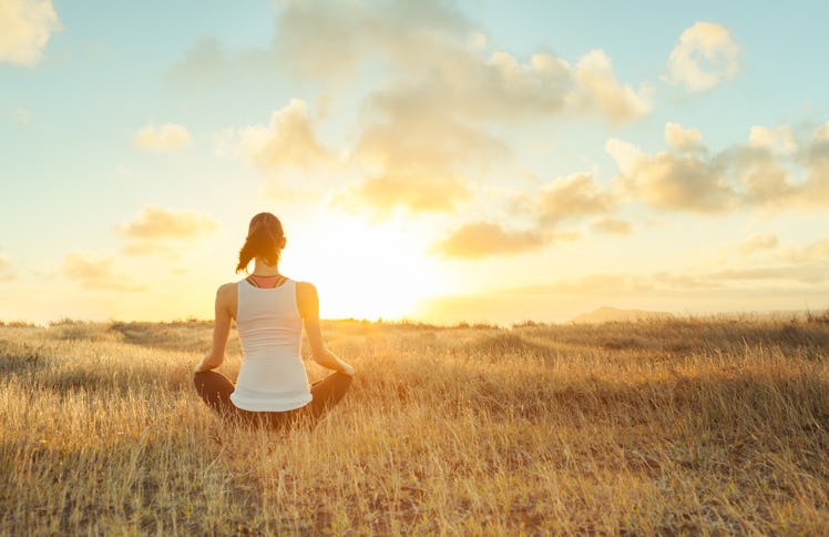 Woman meditating against a beautiful sunset. Mind body spirit. 