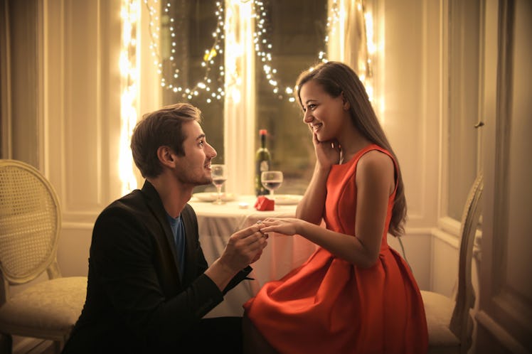 Handsome man proposing a beautiful woman to marry him in an elegant restaurant