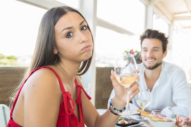 Young woman making an exasperated expression gesture on a bad date at the restaurant