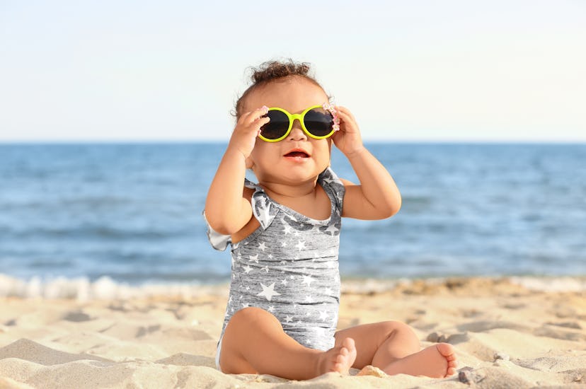 Little girl with sunglasses on beach at resort
