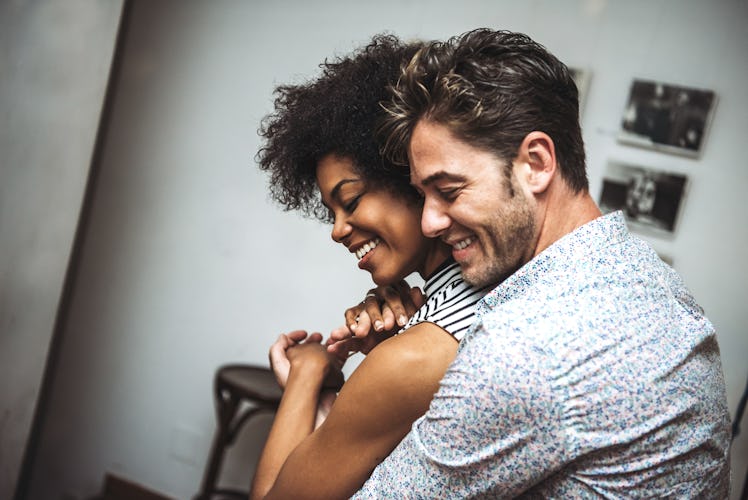 Man embracing woman from back and dancing with eyes closed in bar.