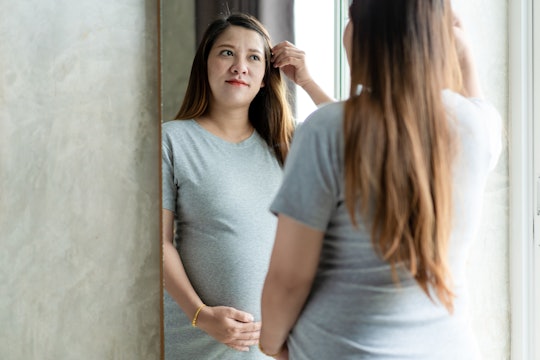 a pregnant woman looking at herself in the mirror