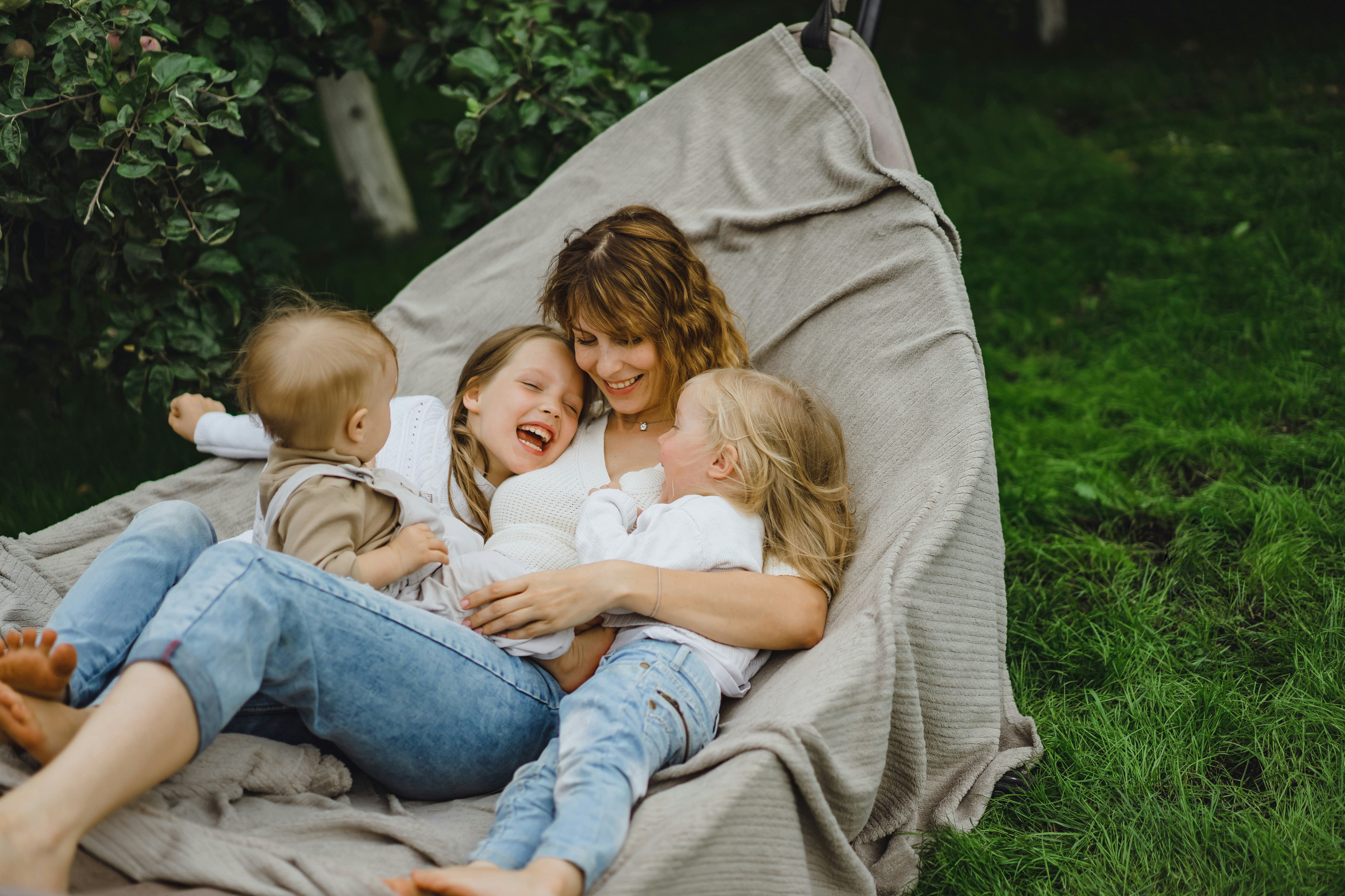 mother with children having fun in a hammock. Mom and kids in a hammock. The family spends time with...