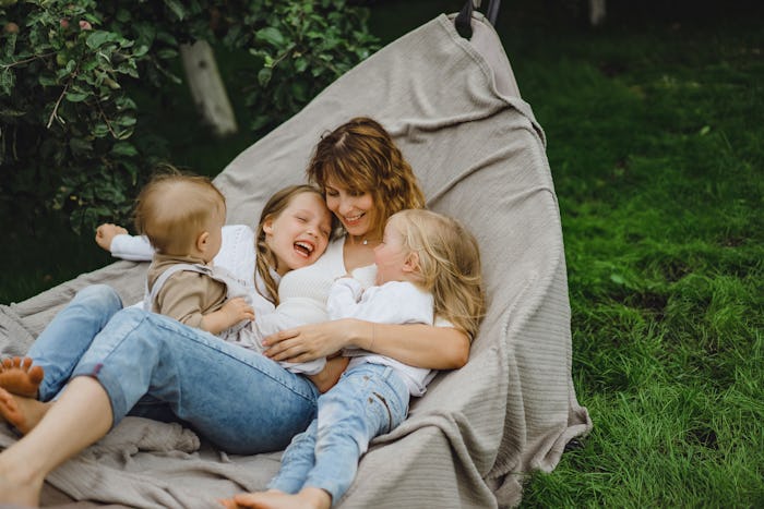 mother with children having fun in a hammock. Mom and kids in a hammock. The family spends time with...
