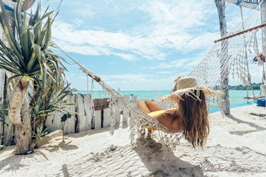 Girl relaxing in hammock in tropical beach cafe, hot sunny day at paradise island