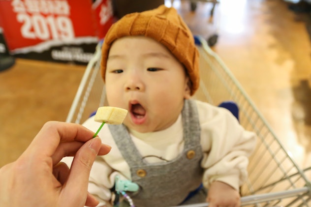 Asian baby eating banana for tasting on the shopping cart