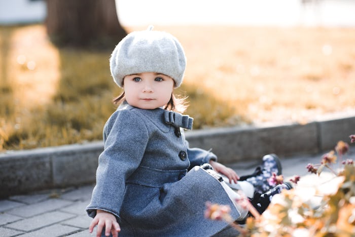 Funny baby girl wearing stylish winter jacket and beret outdoors in park. Autumn season. CHildhood.