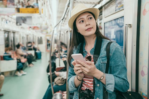 Young asian woman backpacker using smartphone in subway train. girl traveler smiling holding mobile ...