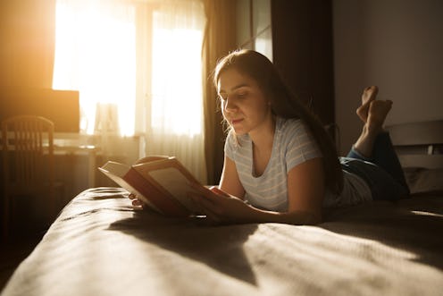 Cute long-haired girl lies and reads a book