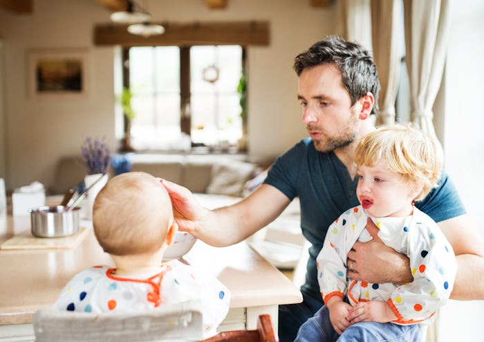 Father feeding two toddlers at home.