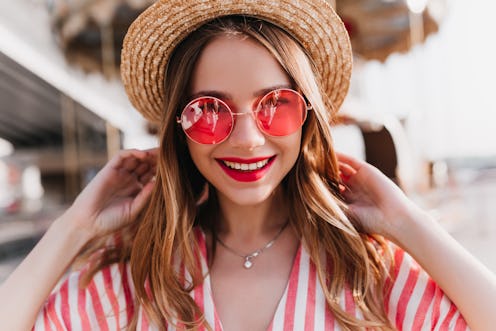 Portrait of sensual blonde woman wears trendy pink summer glasses. Outdoor photo of good-humoured li...