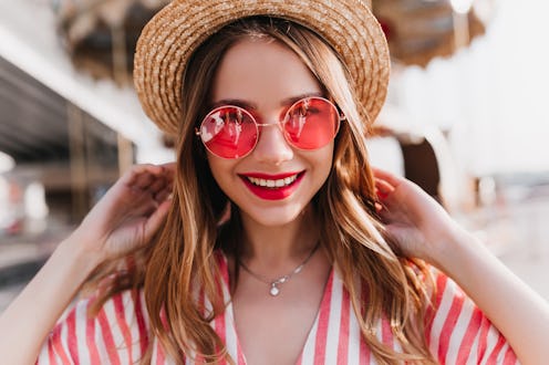 Portrait of sensual blonde woman wears trendy pink summer glasses. Outdoor photo of good-humoured li...