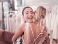 Wedding celebration. Joyful pleasant woman holding a glass with champagne while hugging her best fri...