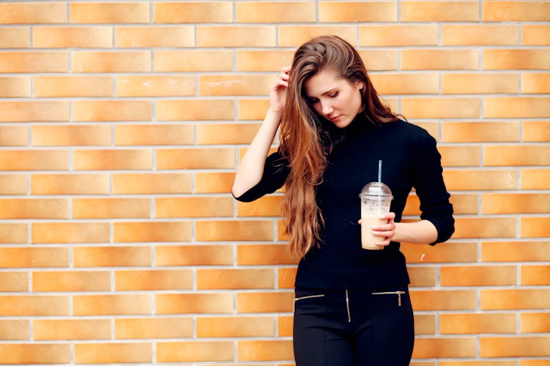 Happy beautiful girl drinking ice coffee in the street