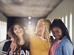 Laughing group of diverse young girlfriends having fun while walking together down a walkway in the ...