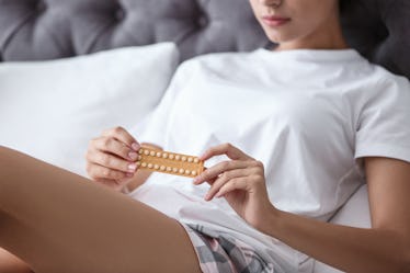 Young woman with birth control pills in bedroom. Gynecology