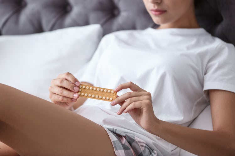 Young woman with birth control pills in bedroom. Gynecology