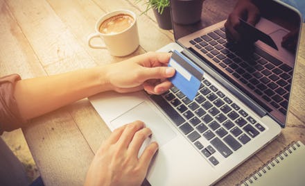 Businessman hand holding credit card and use laptop vintage tone.