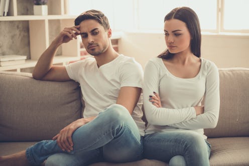 Beautiful young couple is having a quarrel while sitting on sofa at home