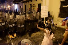 Demonstrators react in front of the police during clashes in San Juan, Puerto Rico, . Thousands of p...