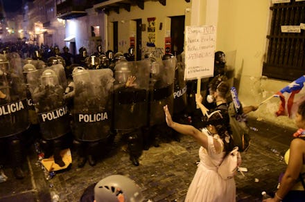 Demonstrators react in front of the police during clashes in San Juan, Puerto Rico, . Thousands of p...