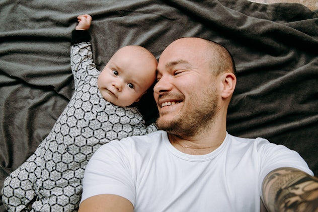 dad and baby take a selfie. They are smiling on a gray background.