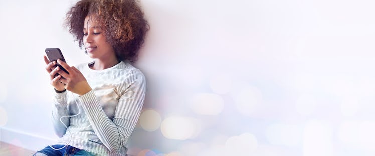 Black woman texting on the floor while charging her phone