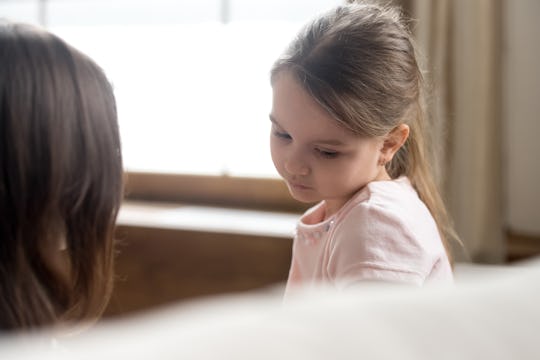 Focus on upset sad small daughter sitting on sofa with mother, mom scold kid for bad behaviour, chil...