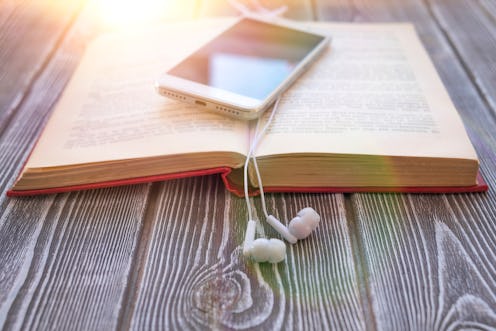 book, smartphone, headphones on a wooden background. audiobook. hobby. free time. recreation. litera...