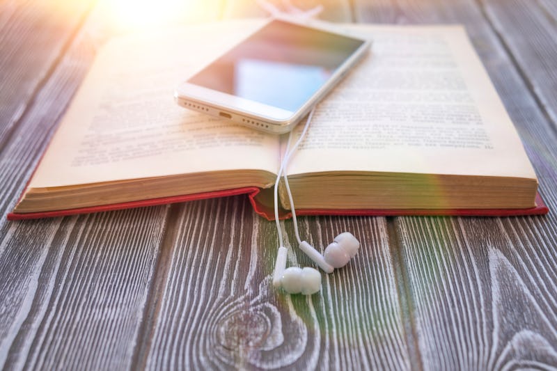 book, smartphone, headphones on a wooden background. audiobook. hobby. free time. recreation. litera...