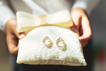 boy holds a magnificent pair of shiny golden wedding rings on a pillow