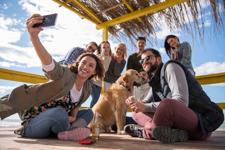 Happy Group Of Friends Hanging Out At Beach House having fun and drinking beer on autumn day