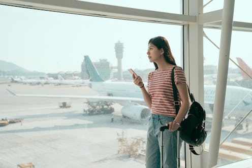 Young asian woman backpacker in airport waiting for airplane. japanese female holding mobile phone s...