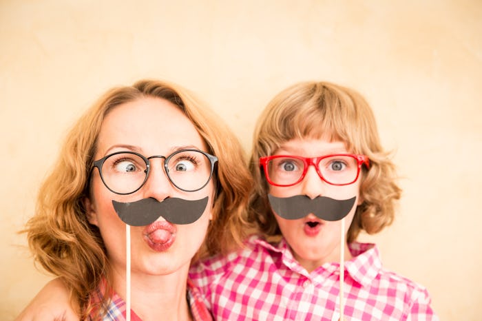 Mother and child with fake mustache. Happy family playing in home