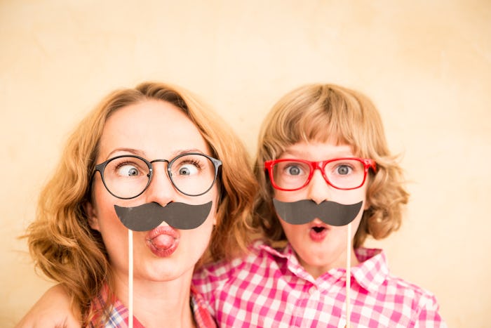 Mother and child with fake mustache. Happy family playing in home 