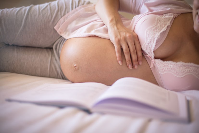 And if it's in the stomach, read to your baby every day. Pregnant woman reading book. Close up.