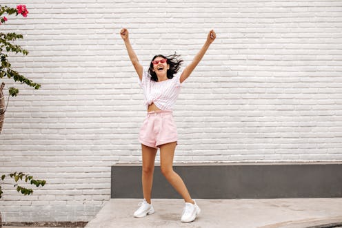 Debonair girl jumping with hands up on street. Outdoor shot of blithesome female model having fun in...