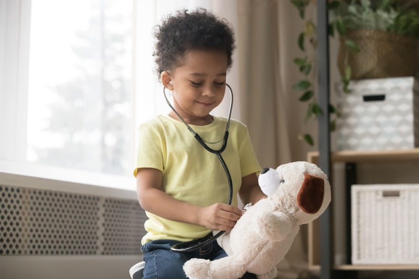 Cute little toddler african american boy playing funny game as doctor holding stethoscope listening ...