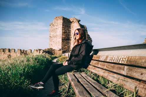 Girl with sunglasses sitting on a bench sunbathing on sinop