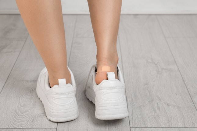 Female with plastered heel on wooden floor, closeup view. Space for text