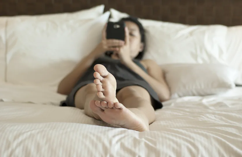 Young woman using smart phone on the bed