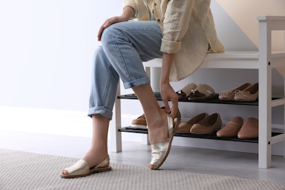 Woman putting on shoes indoors, closeup. Stylish hallway interior