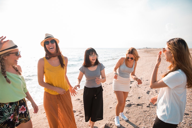 Group of women friends having fun and dancing on the beach. Holiday concept