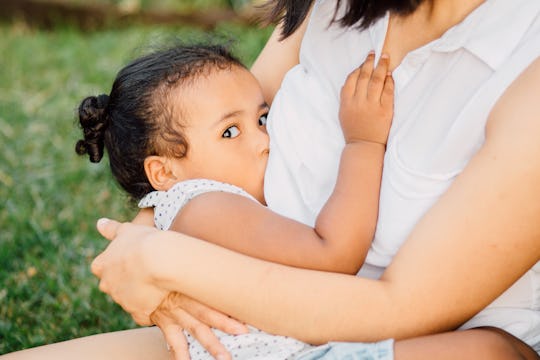 mom nursing a toddler girl outside