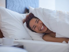Young happy black woman lying in bed.