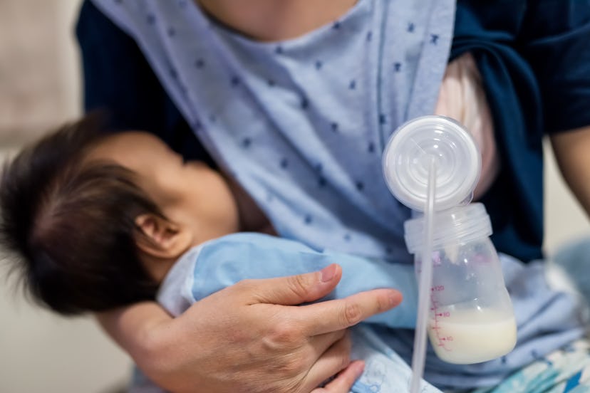 Busy mother pump milk into Automatic breast pump machine and feed breastmilk by another boob to her ...