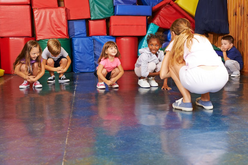 Children doing gymnastics in physical education with nursery teacher in preschool