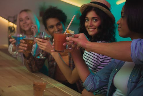 selective focus of multicultural friends with cocktails having party together in bar